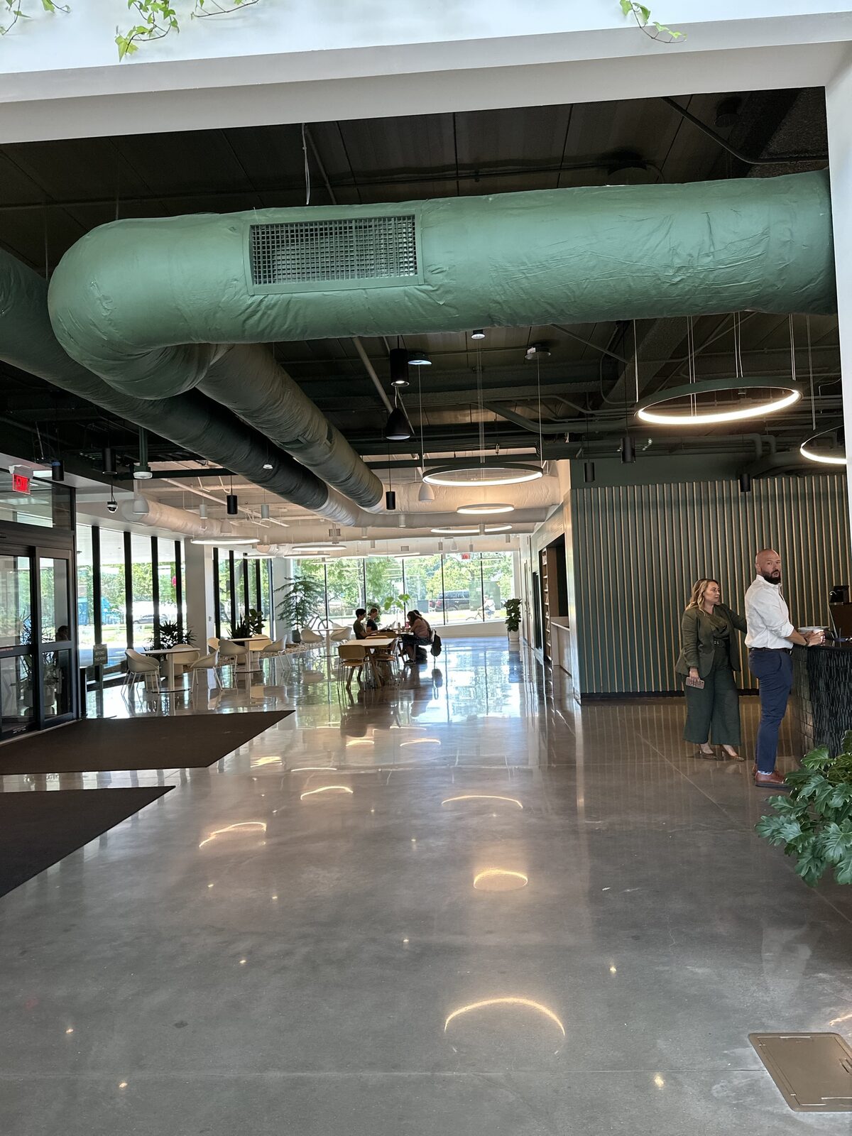 A modern lobby lounge with exposed ductwork and resident seating at a Convivium Living community