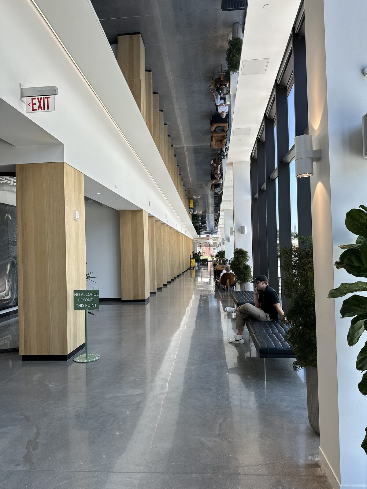 A sunlit interior walkway with wood columns and lounge seating at a Convivium Living community