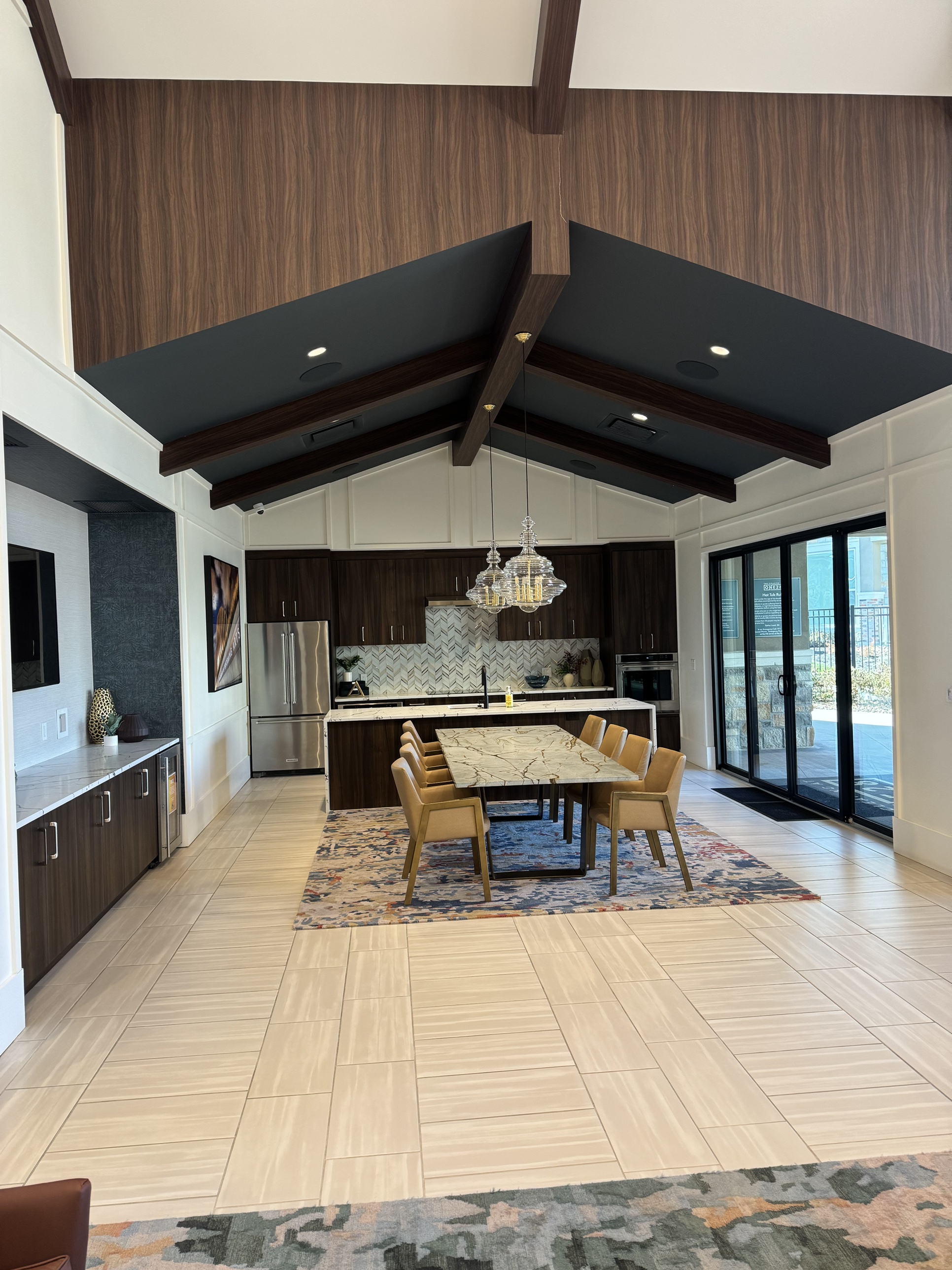 The clubhouse dining and kitchen lounge at a Convivium Living community, with vaulted wood-beam ceilings