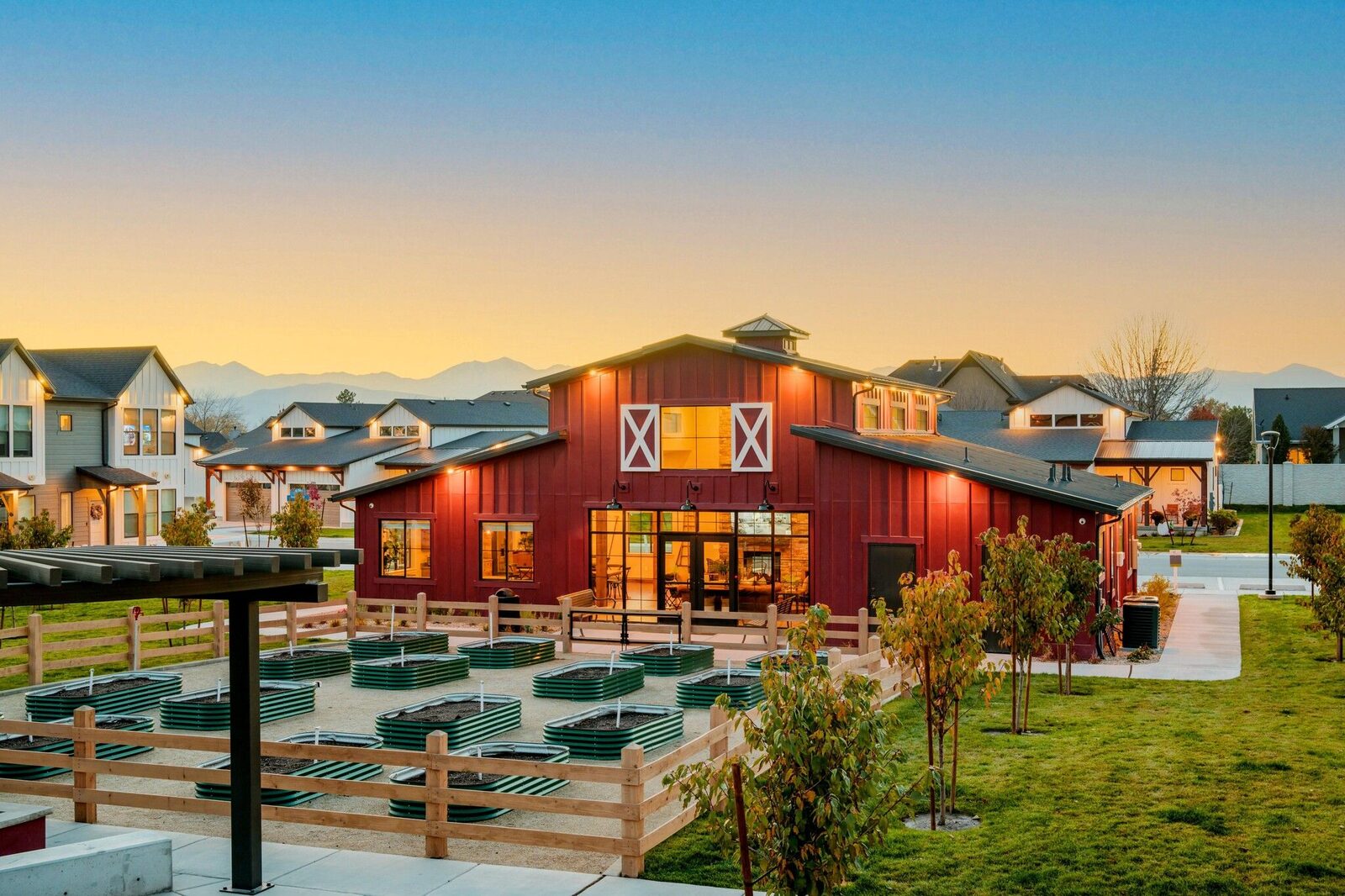A community clubhouse and garden plots at a DanReDev community at dusk