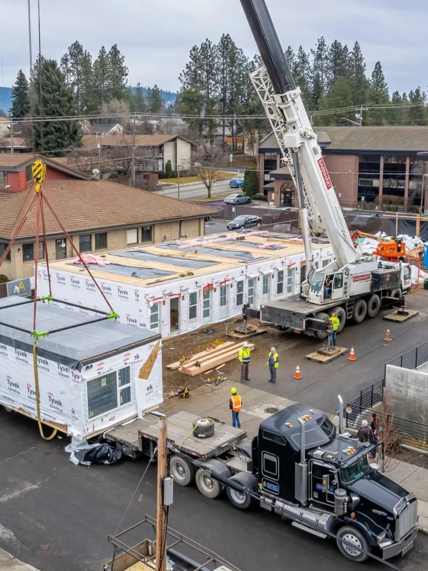 A second-story modular unit lifted into place by crane on a DanReDev project