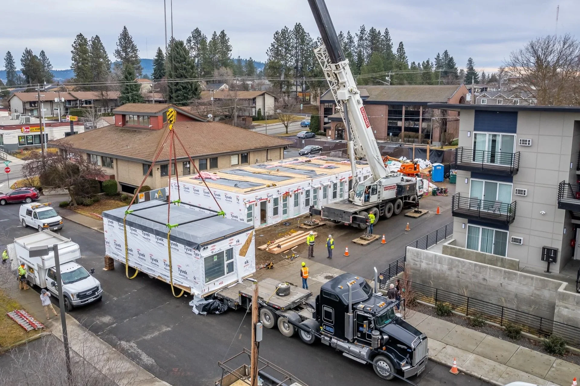 An aerial view of a modular building unit being lifted into place on a DanReDev project