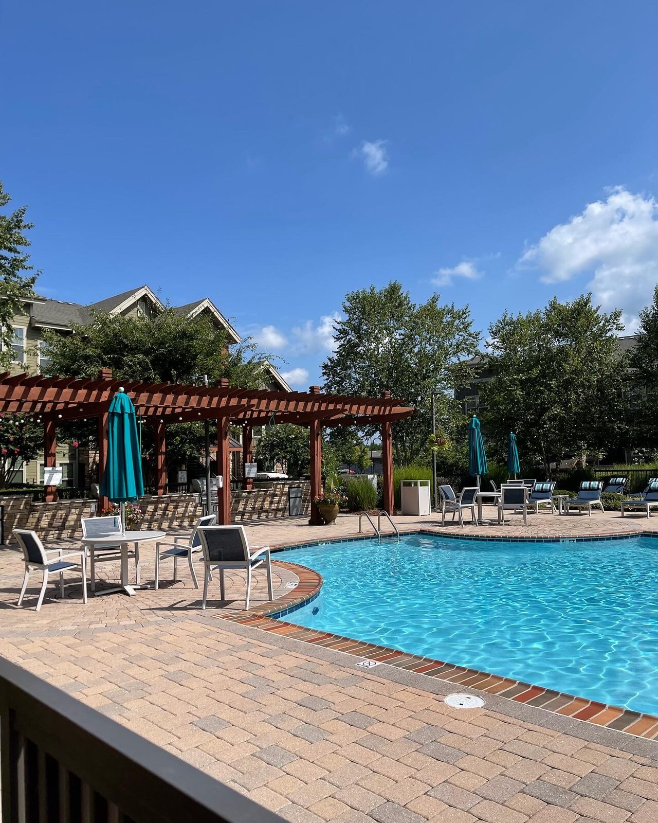 A Design Build Affordable community pool with string lights and lounge seating
