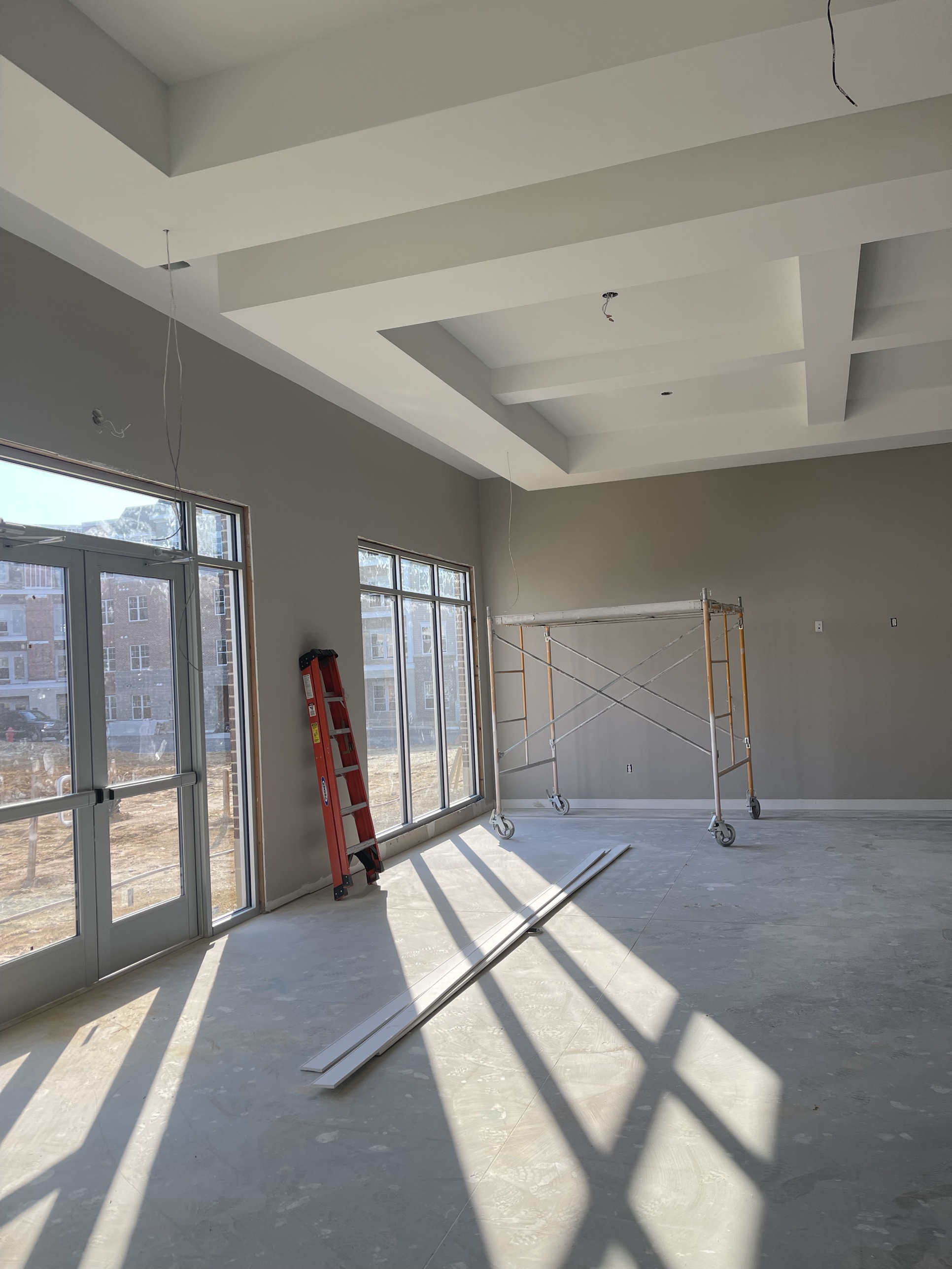A clubhouse interior taking shape, beamed ceilings framed in ahead of drywall and finishes, the shared space that will anchor the community once it's done