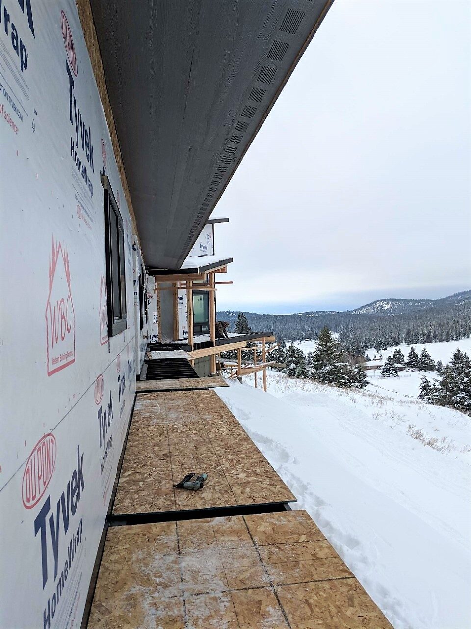 A DEK Builds home wrapped in house wrap under construction on a mountainside