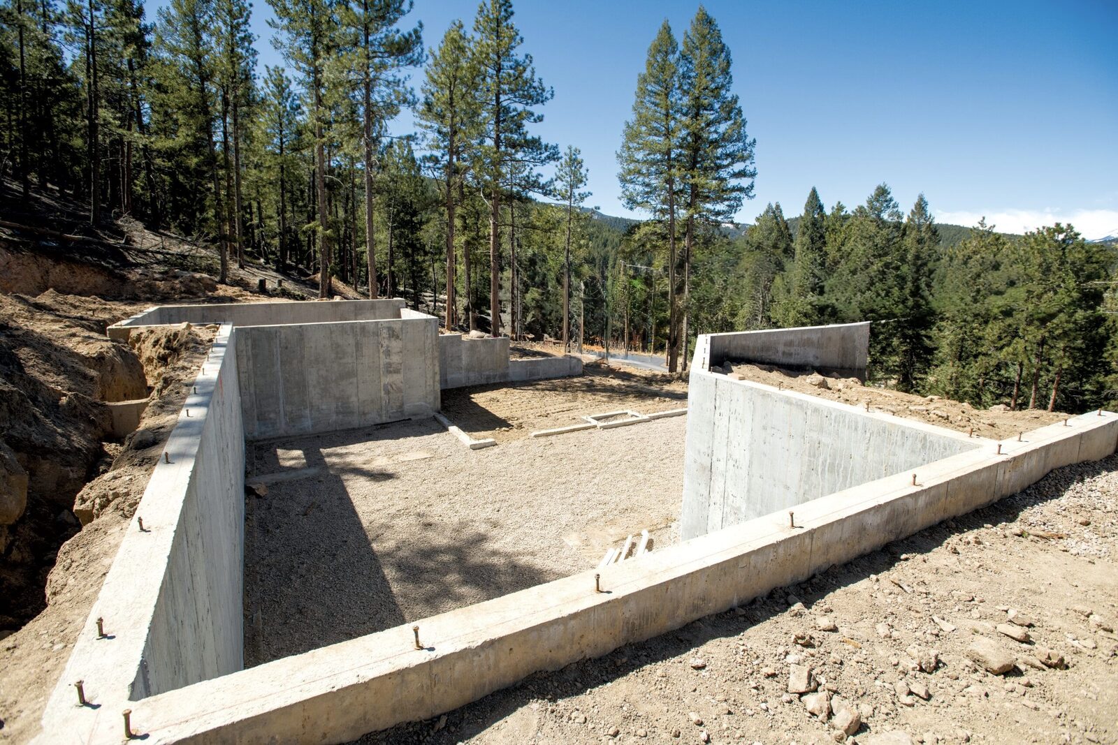 Foundation work for a DEK Builds home on a forested mountainside lot