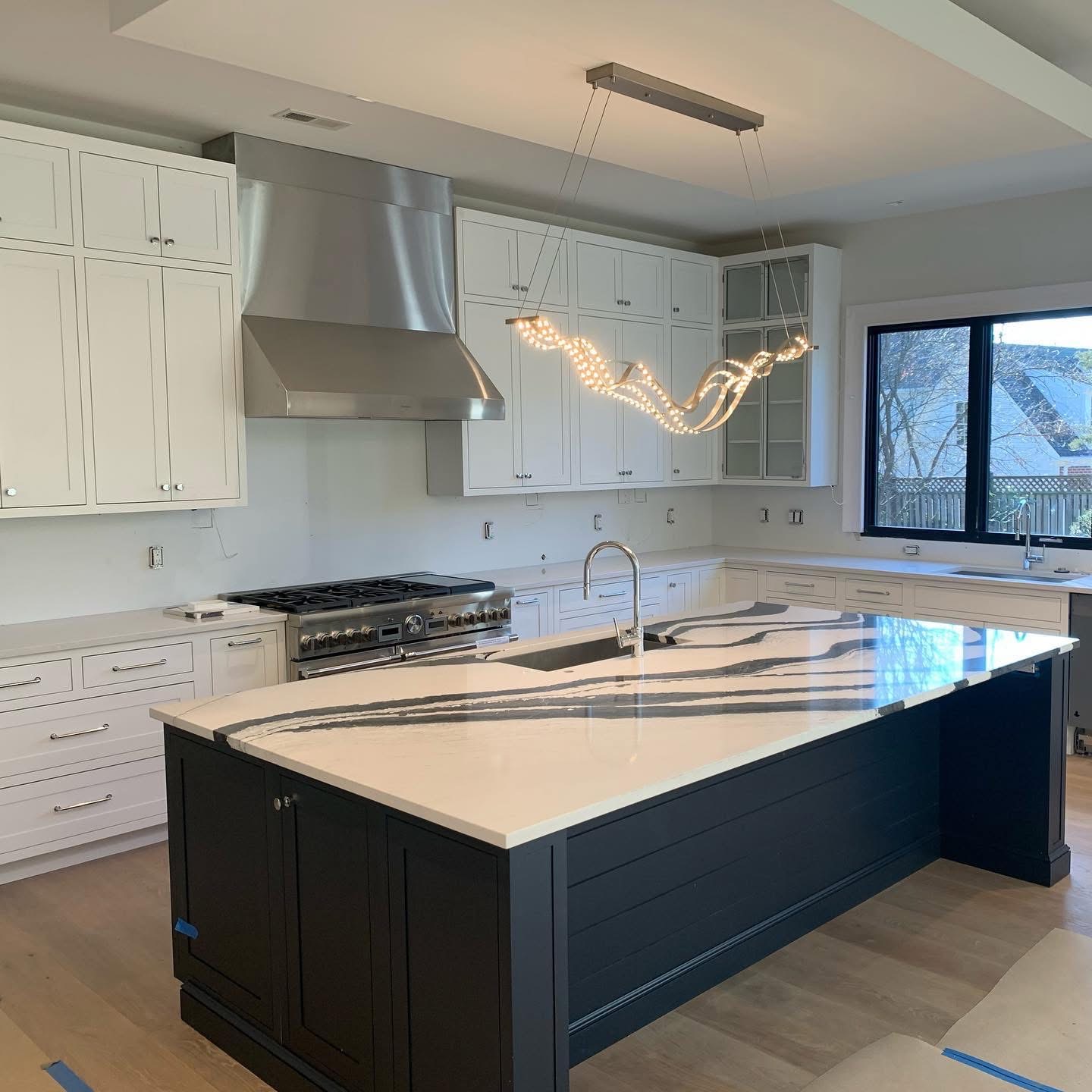 A kitchen mid-finish at a Forge Development property, waterfall quartz island and stainless appliances ready for move-in