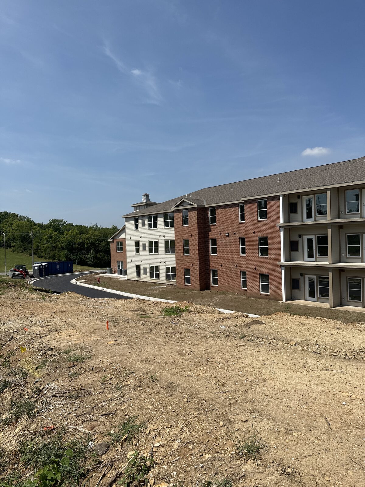 A brick apartment building under construction with a dumpster and equipment