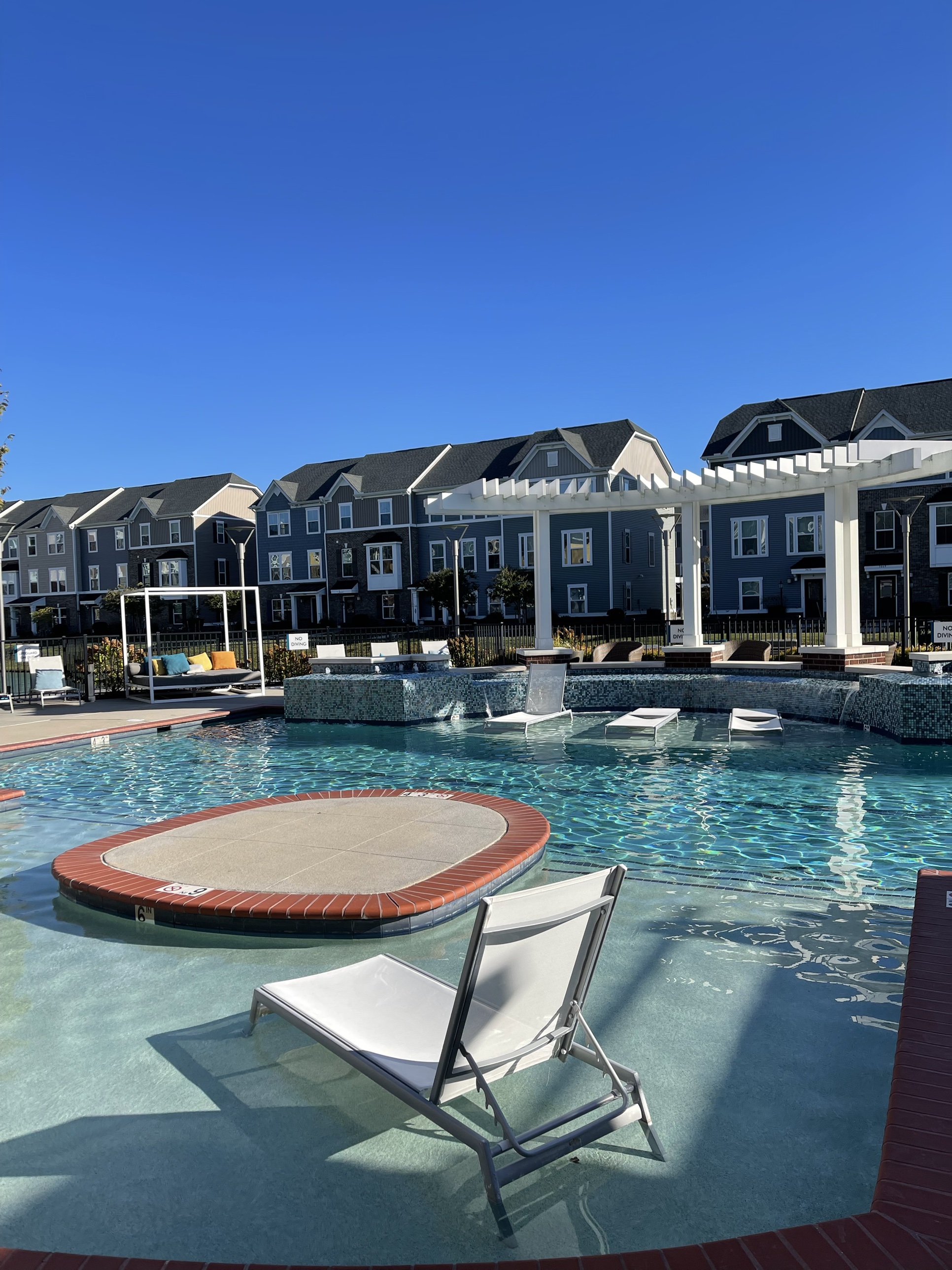 A resort-style pool and lounge deck at a Kaufman Development community, framed by townhomes