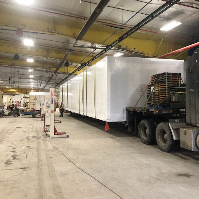 Two shrink-wrapped Oldivai Project Zero modules staged on trailers inside the factory