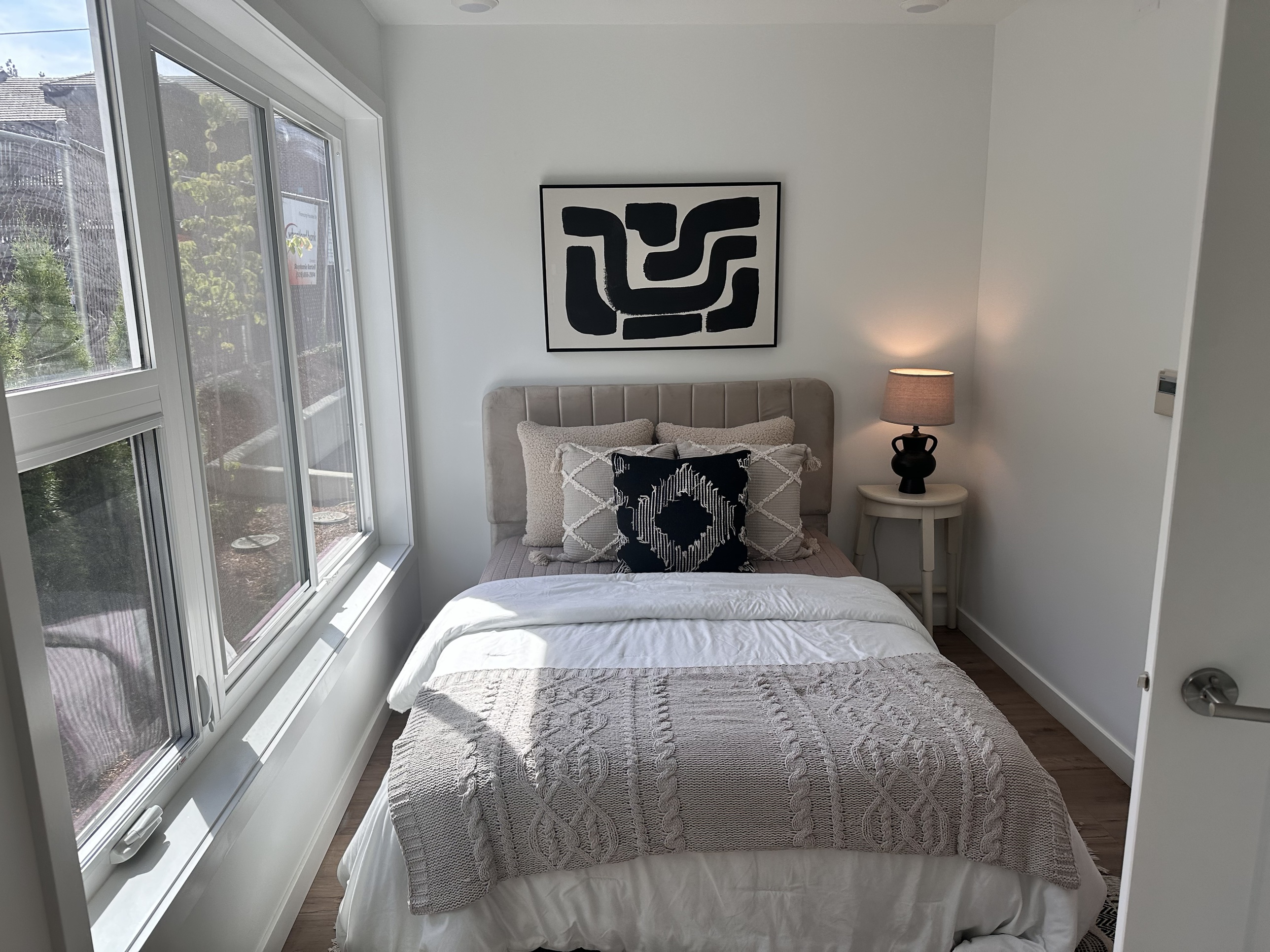 A furnished bedroom inside a completed Oldivai Project Zero unit, with a large window and modern decor