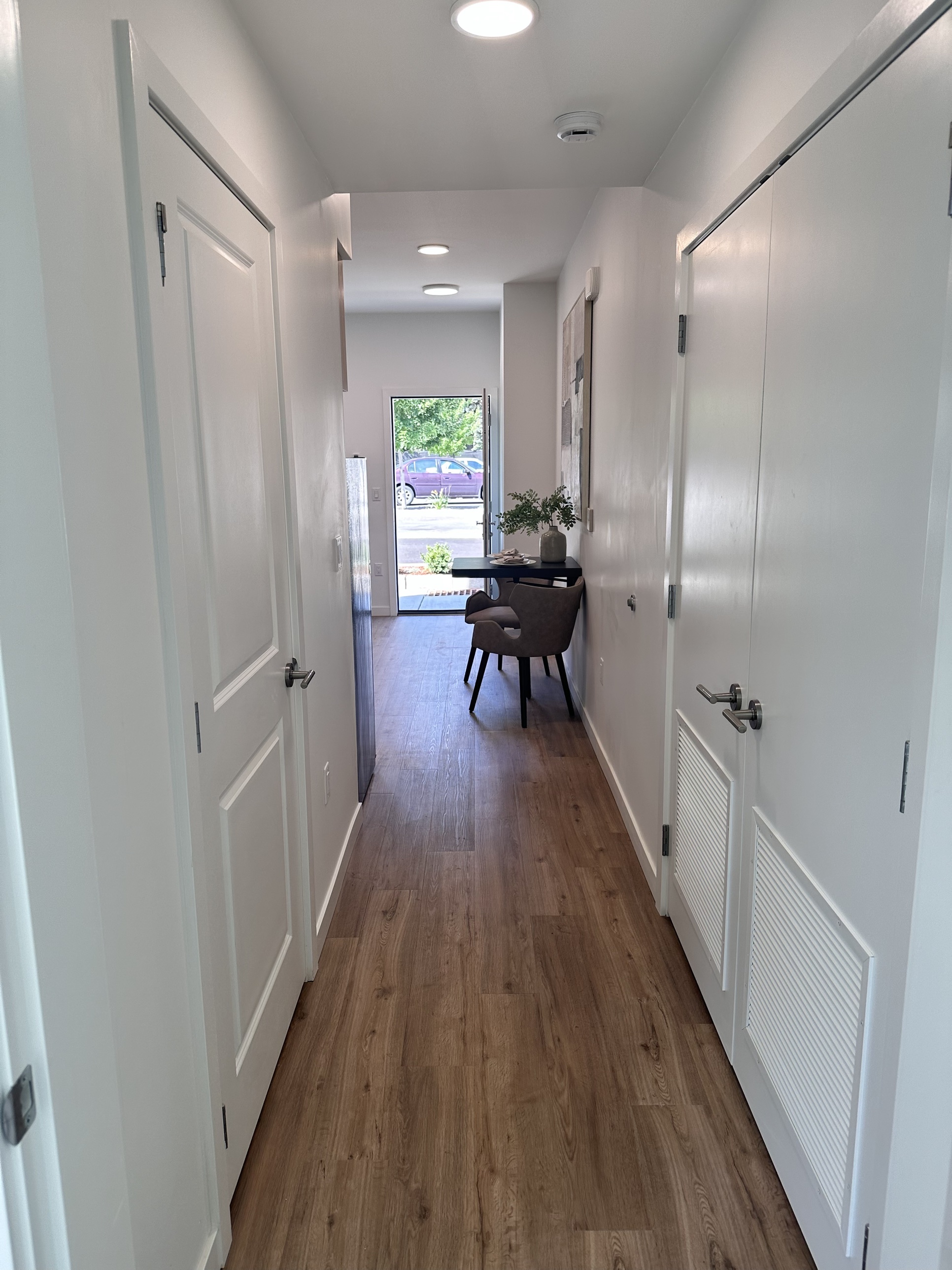 A hallway inside a finished Oldivai Project Zero unit, leading past closet doors to a small dining area near the entrance