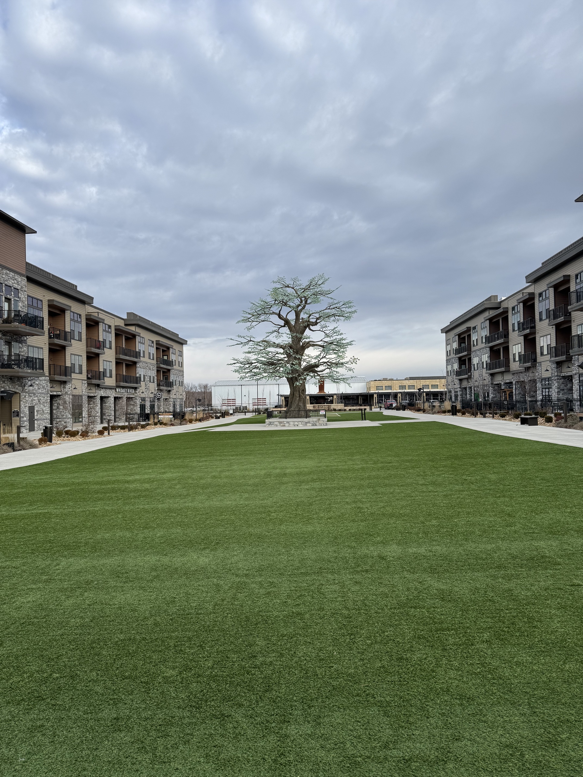 A landscaped town green surrounded by apartment buildings in a Prophesy Capital target market